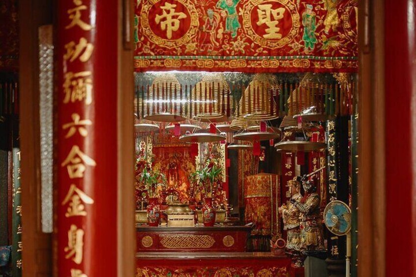 A traditional Chinese altar with incense burners, a statue, and red decorations. 4