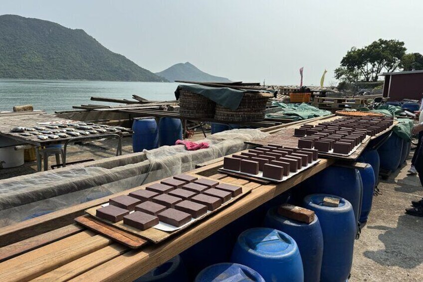 A dock with wooden pallets, barrels, and bricks. 2