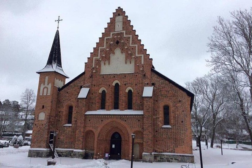 A brick church with a tall steeple and a snow-covered roof. 3