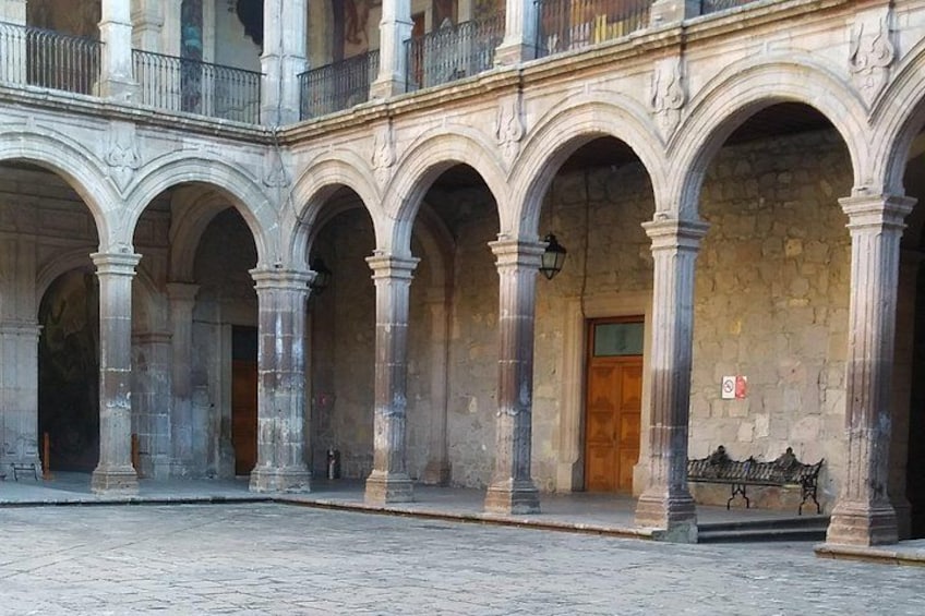 Une cour avec des arches en pierre, une porte en bois et un banc. 2