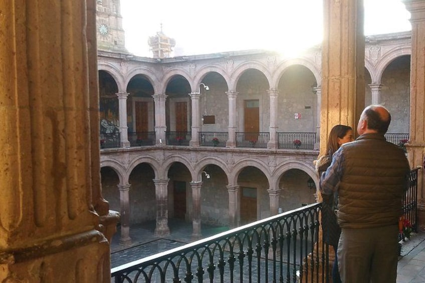A historical building with arched balconies and a reflective water feature. 2