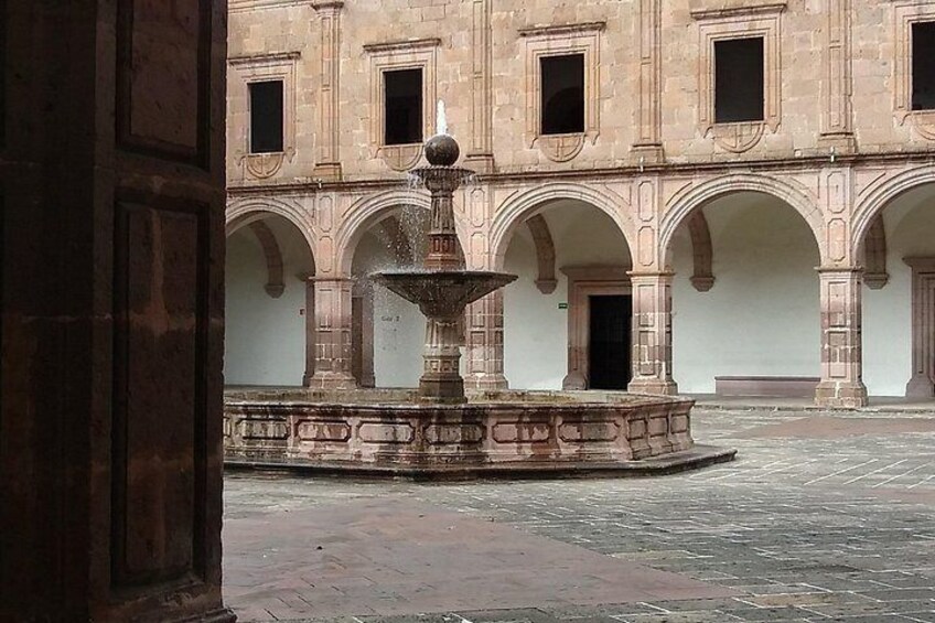Un patio con una fuente, arcos y la fachada de un edificio. 2