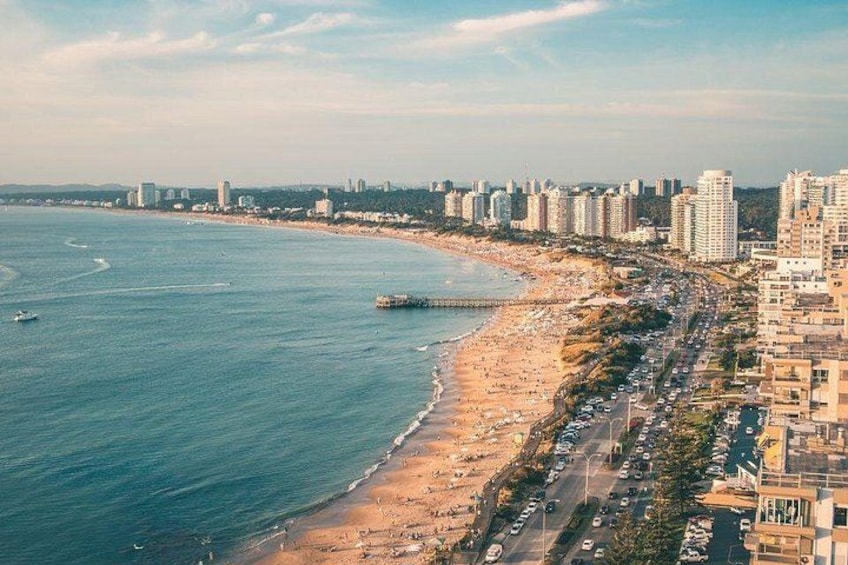 Eine Küstenstadt mit Strand, Hochhäusern und einem Steg. 5