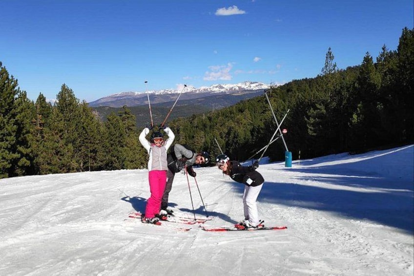 Skiers on a snowy slope with trees and mountains in the background. 2