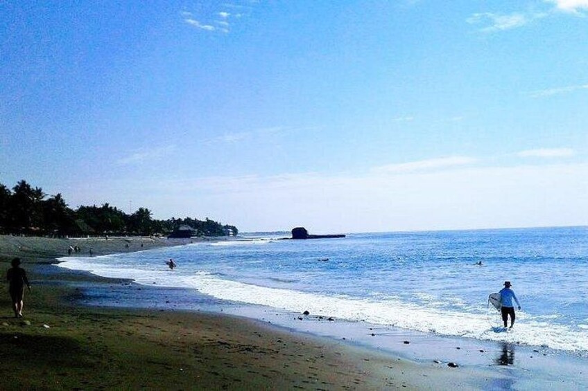 A beach with people walking along the shore, a clear sky, and a calm sea. 5