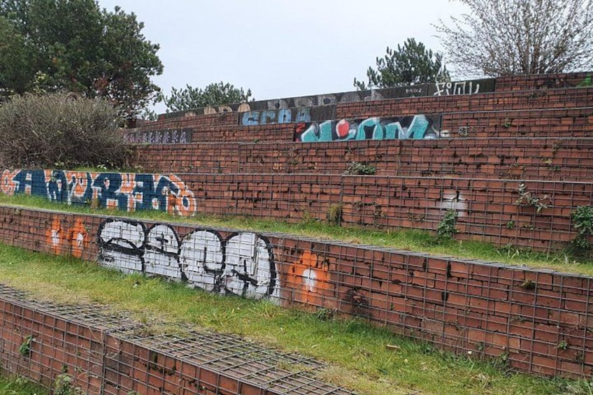 A brick wall with graffiti and a metal fence. 2