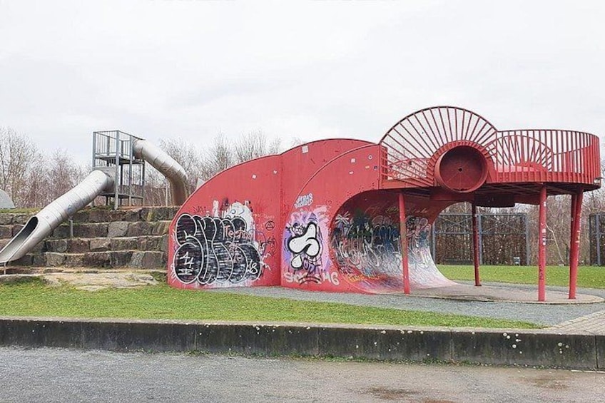 A red playground structure with graffiti, a slide, and a metal staircase. 3