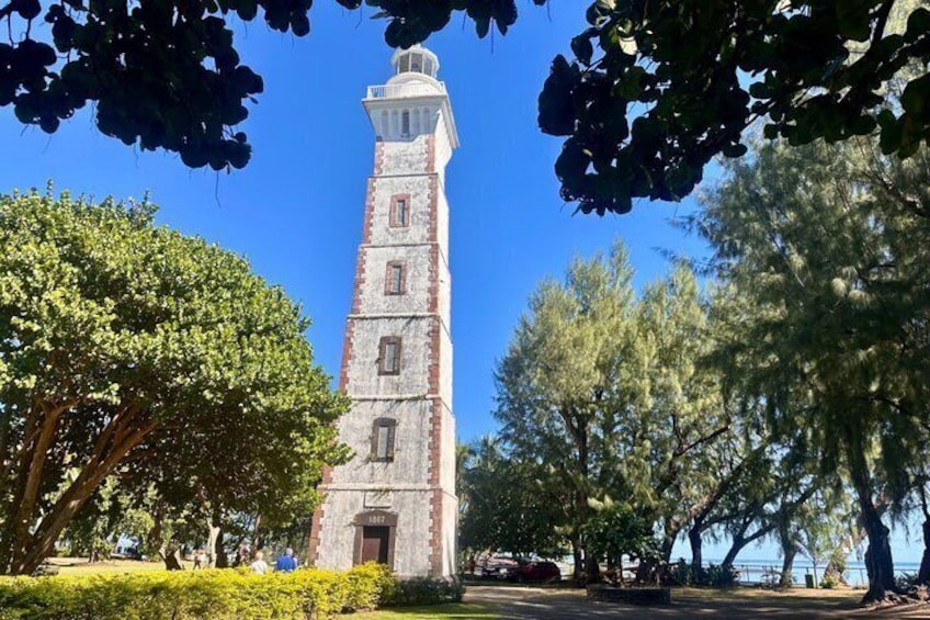 A tall tower with a clock, surrounded by trees and a clear sky. 3