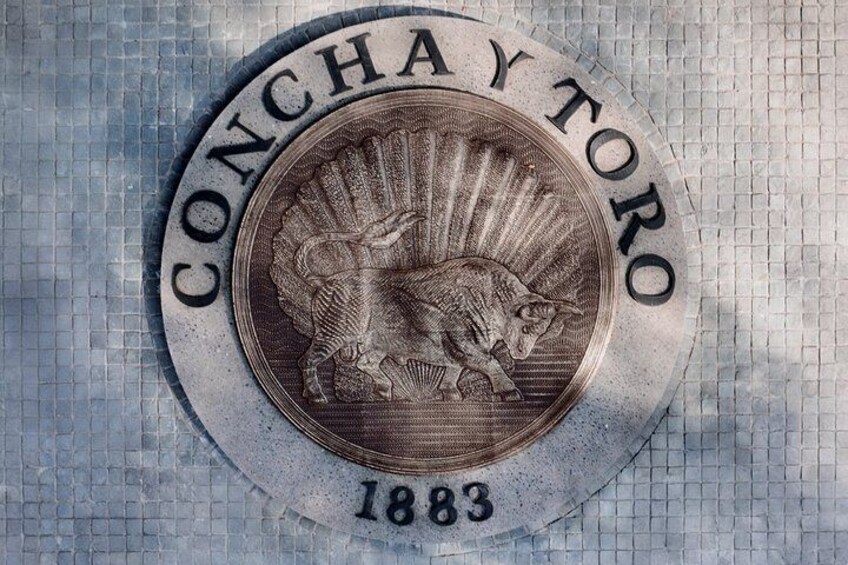 Una moneda con un toro y la inscripción 'CONCHAY TORO 1883' sobre un fondo de baldosas. 1