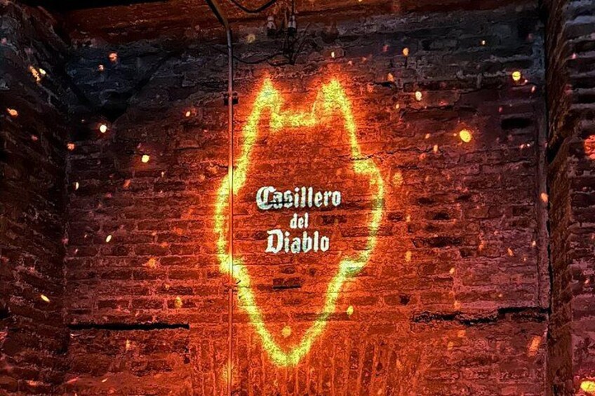 Een bakstenen muur met een neonbord in de vorm van een hart waarop 'Casillero del Diablo' staat. 2