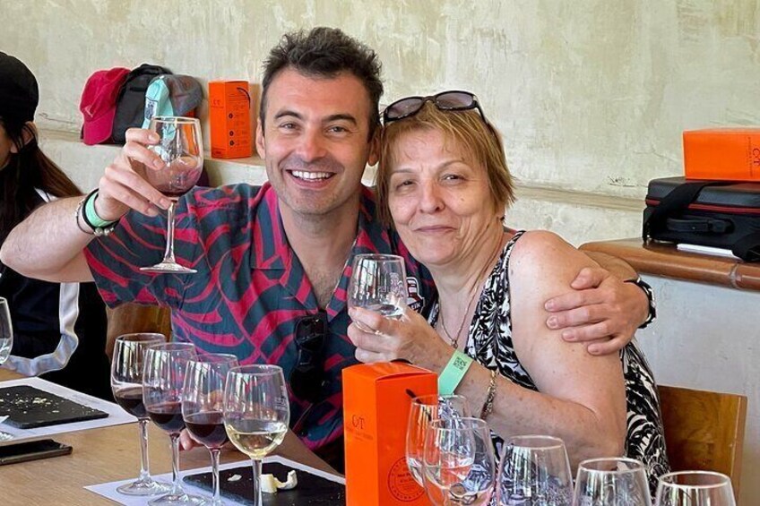 Dos personas sentadas en una mesa con copas de vino y una caja. 4