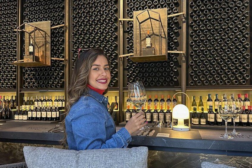 Una persona sentada en la barra, con una estantería de vinos al fondo. 2