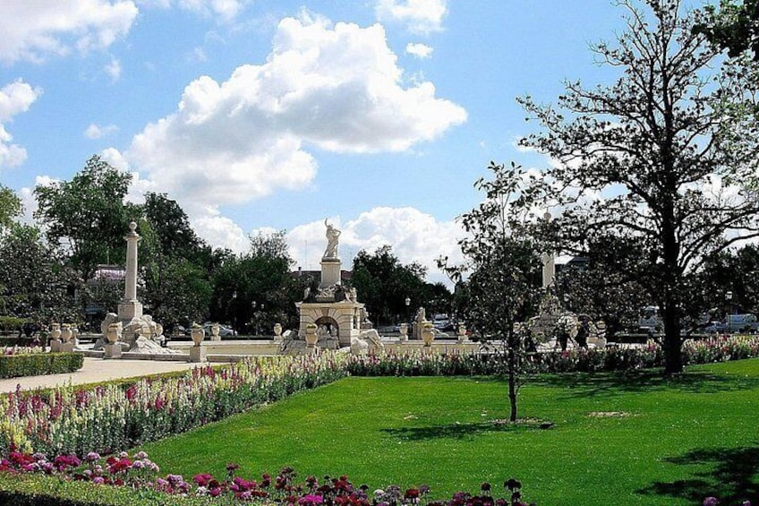Un parque con estatuas, una fuente y un césped bien cuidado. 2