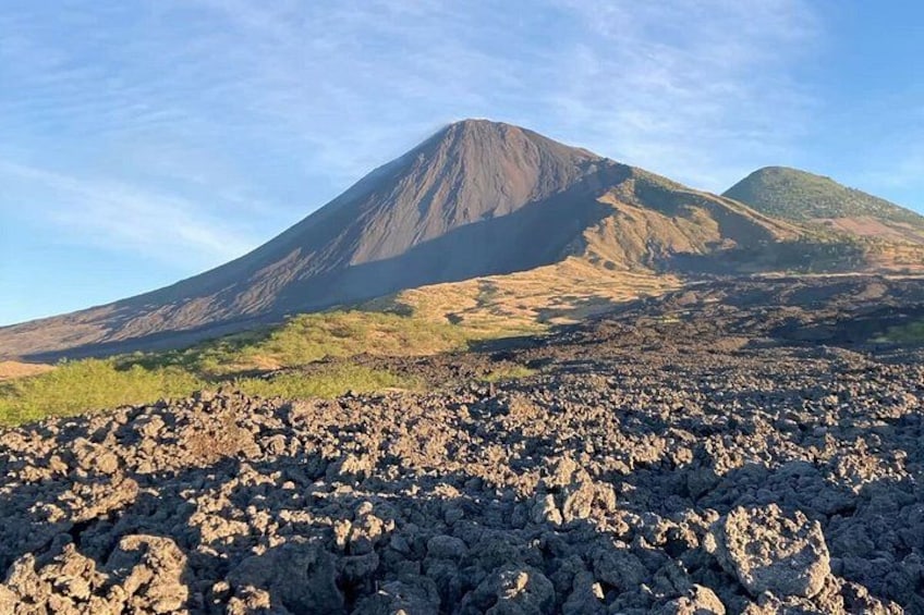 A volcanic landscape with a prominent mountain in the background and rocky terrain in the foreground. 2