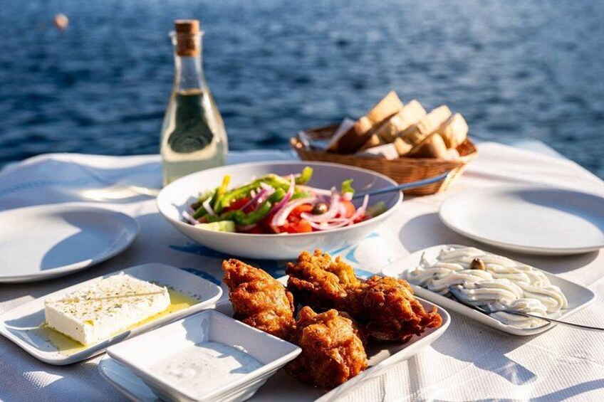 Un tavolo con cibo e bevande con vista sul mare. 3
