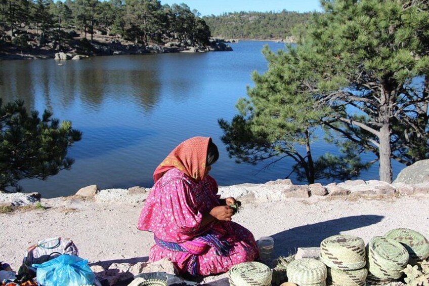 A person sitting by a lake with fishing gear and baskets. 2