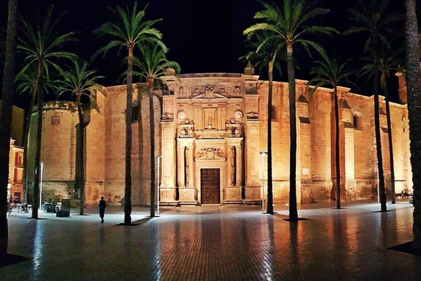 Un edificio histórico con palmeras frente a él, iluminado por la noche. 3