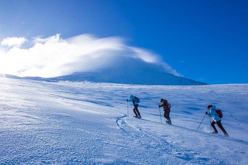 Drie skiërs op een besneeuwde helling met een berg op de achtergrond. 1