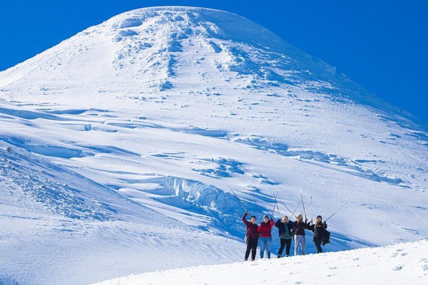 Een groep mensen staat op een met sneeuw bedekte helling, met een berg op de achtergrond. 4