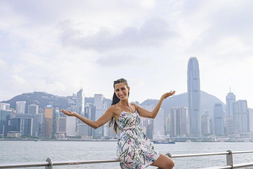 A person in a floral dress by a waterfront with a city skyline in the background. 3
