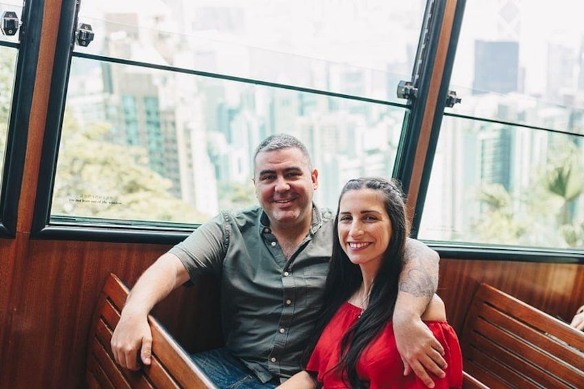 Two people sitting on a bench inside a building with large windows. 5