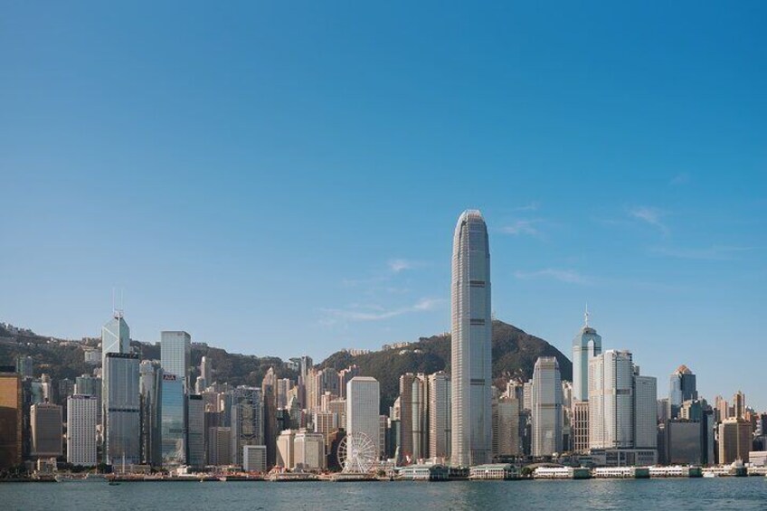 A city skyline with a prominent skyscraper, a Ferris wheel, and a body of water in the foreground. 2