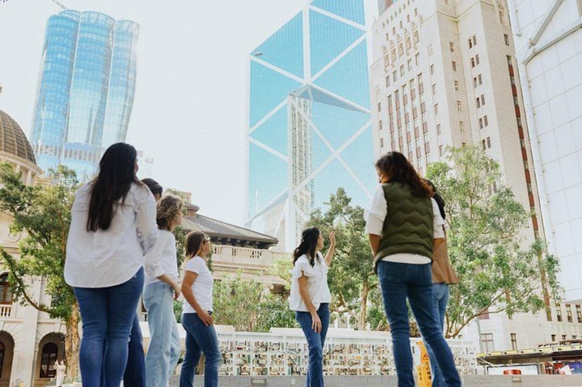 A group of people standing outdoors in an urban setting with modern buildings in the background. 4