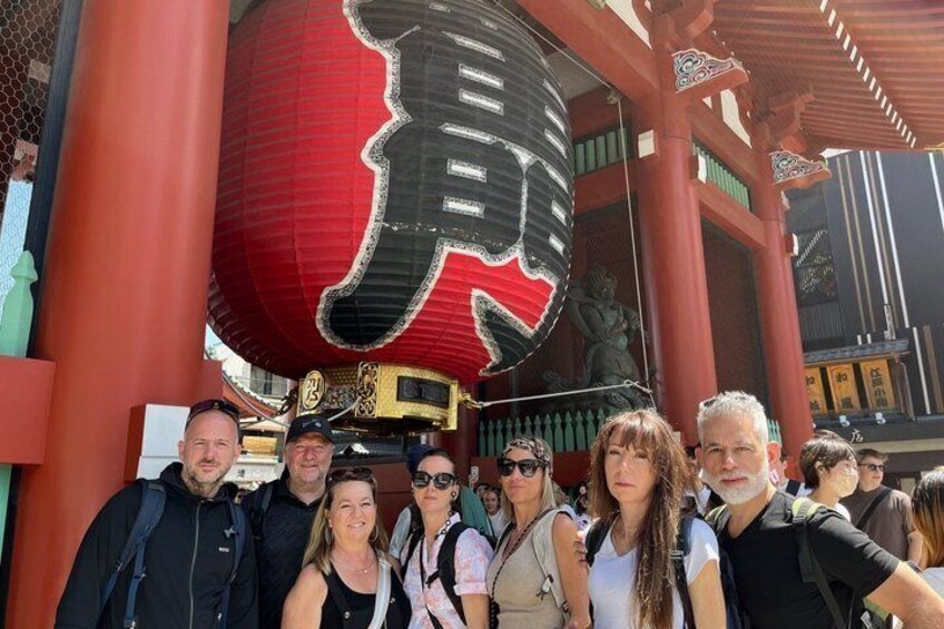Un groupe de personnes se tient devant un portail torii japonais traditionnel, surmonté d’une grande lanterne rouge. 2