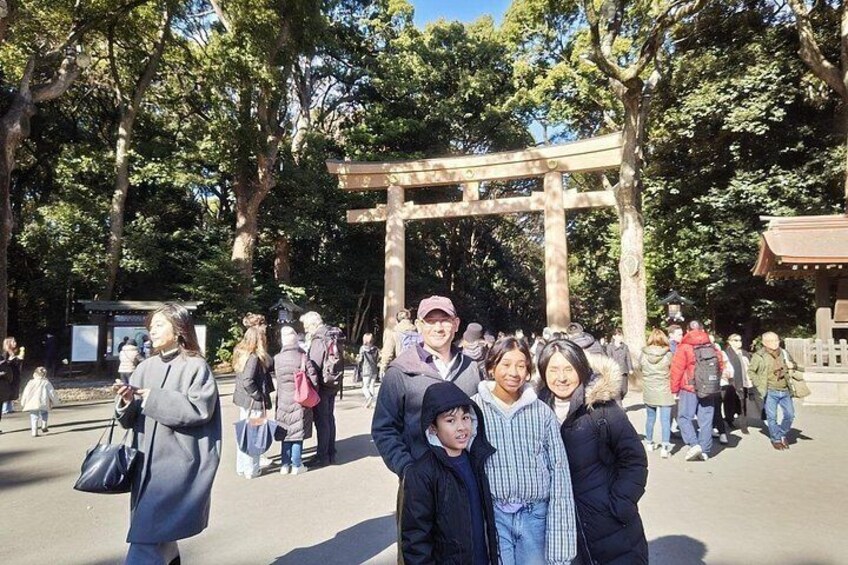 Een groep mensen staat voor een traditionele Japanse torii-poort in een park. 2