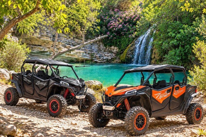 Zwei Geländewagen auf felsigem Untergrund in der Nähe eines Wasserfalls und eines türkisblauen Sees. 4