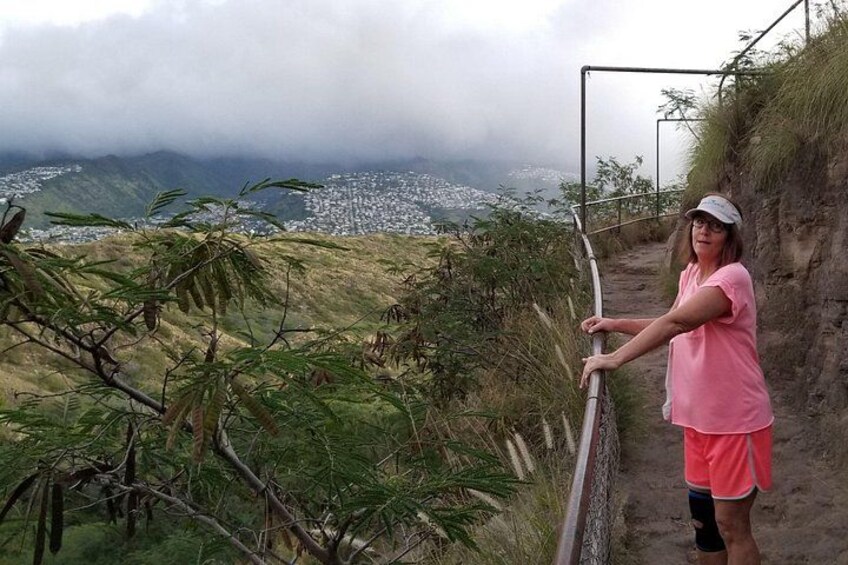 Una persona parada en un sendero con vista a un pueblo y montañas al fondo. 5