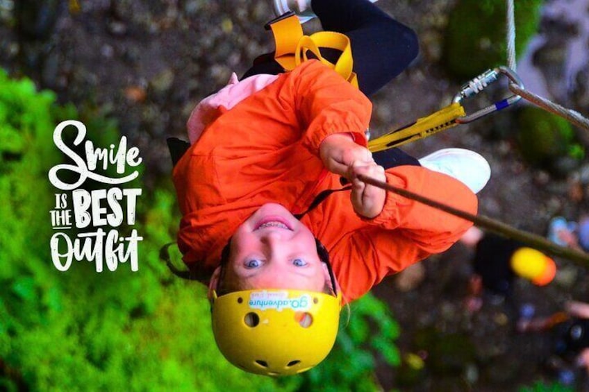 A person upside down on a bungee jump with a helmet and harness, surrounded by greenery. 4