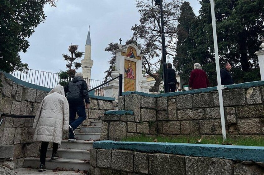 People ascending stone steps towards a religious monument with a cross. 3