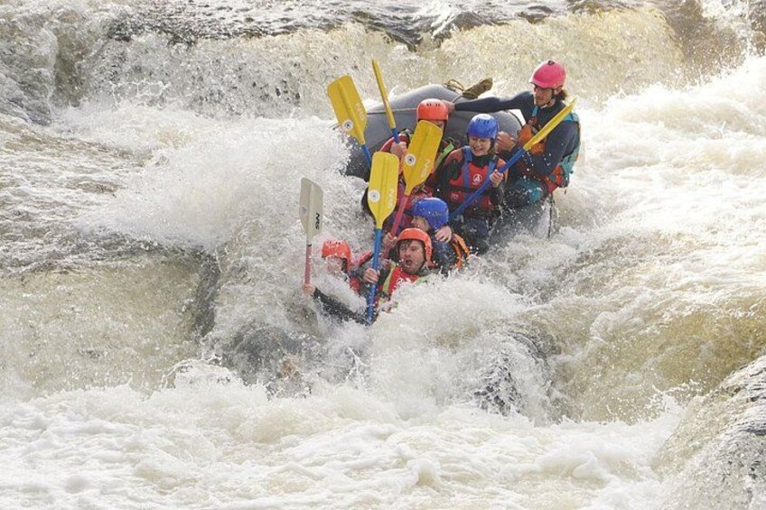 A group of people in a raft navigating through a turbulent river. 1