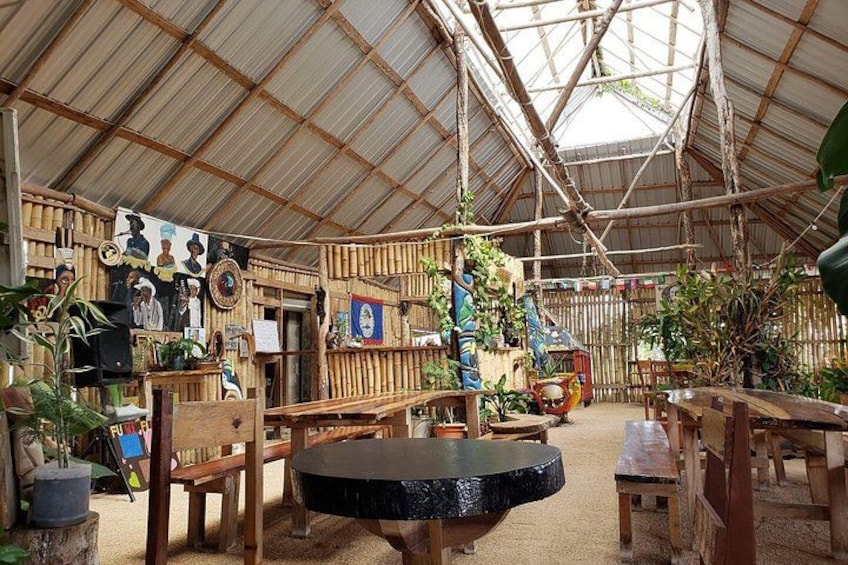 A rustic indoor space with bamboo walls, wooden furniture, and various decorations. 1