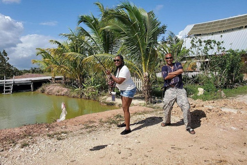 Two people standing near a body of water with palm trees and a building in the background. 4