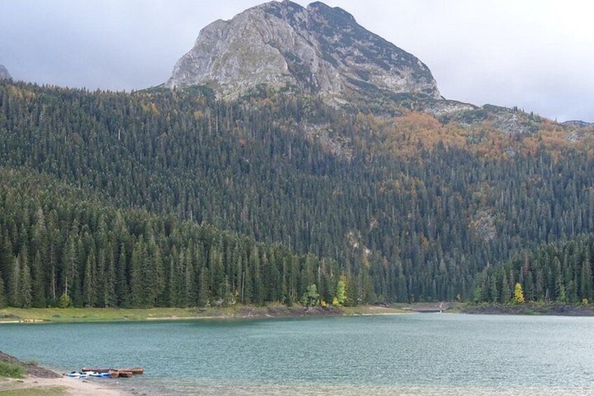 A lake surrounded by dense forest and a prominent mountain. 5