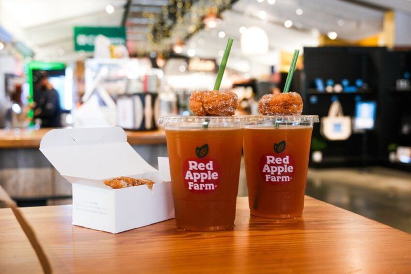 Dos bebidas heladas de Red Apple Farm con decoración de rosquillas azucaradas sobre una mesa de madera. 3