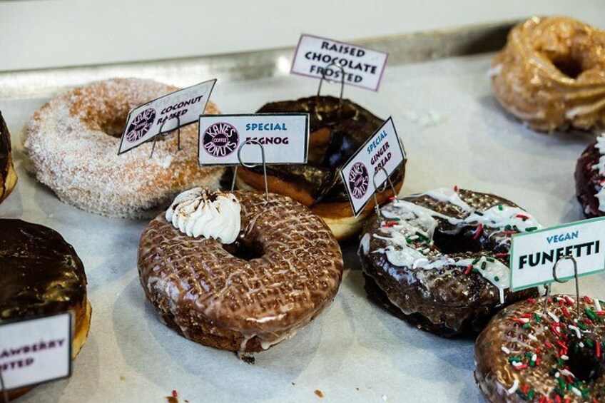 Forskellige donuts med etiketter, der angiver smagsvarianter som chokolade, kokos og vegansk. 4