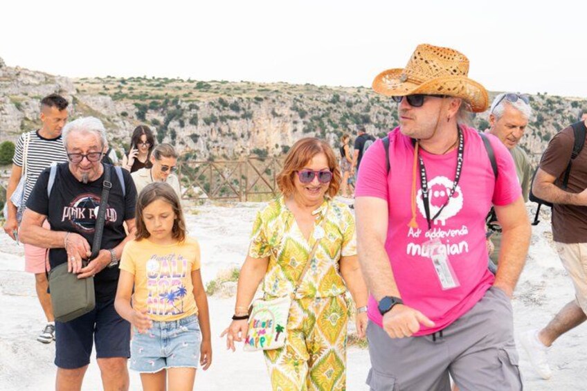 A group of people walking on a beach with rocky terrain in the background. 2