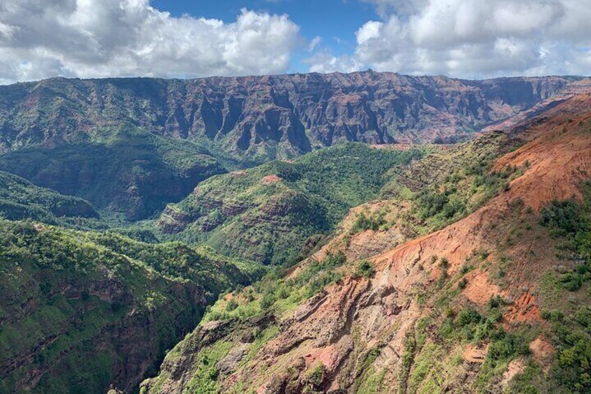 A mountainous landscape with green valleys and red cliffs. 3