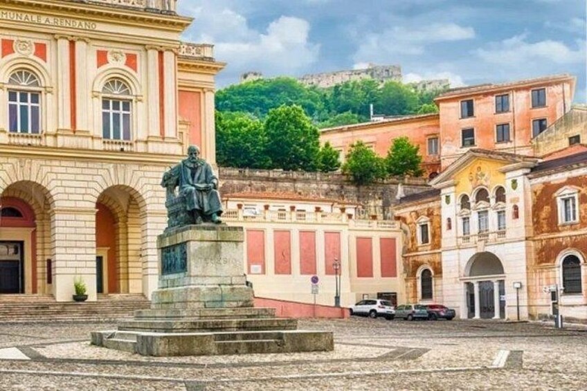 A statue in a square with historic buildings in the background. 3