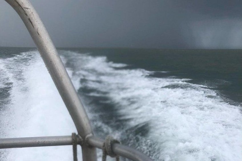 A turbulent sea with waves crashing against a metal railing. 2