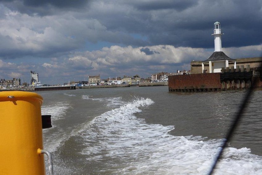 A body of water with waves, a lighthouse, and buildings in the background. 3