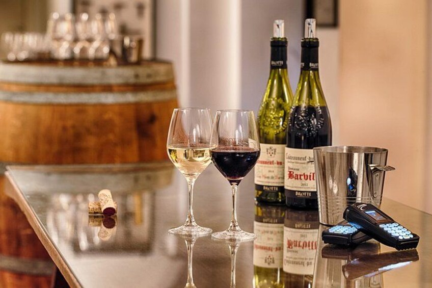 Un bar avec des verres à vin, des bouteilles et une télécommande posés sur une surface réfléchissante. 1