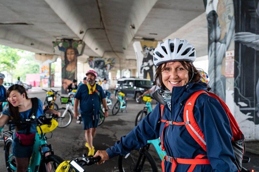 Un groupe de cyclistes se trouve sous un pont, certains portent des casques et des sacs à dos. 2