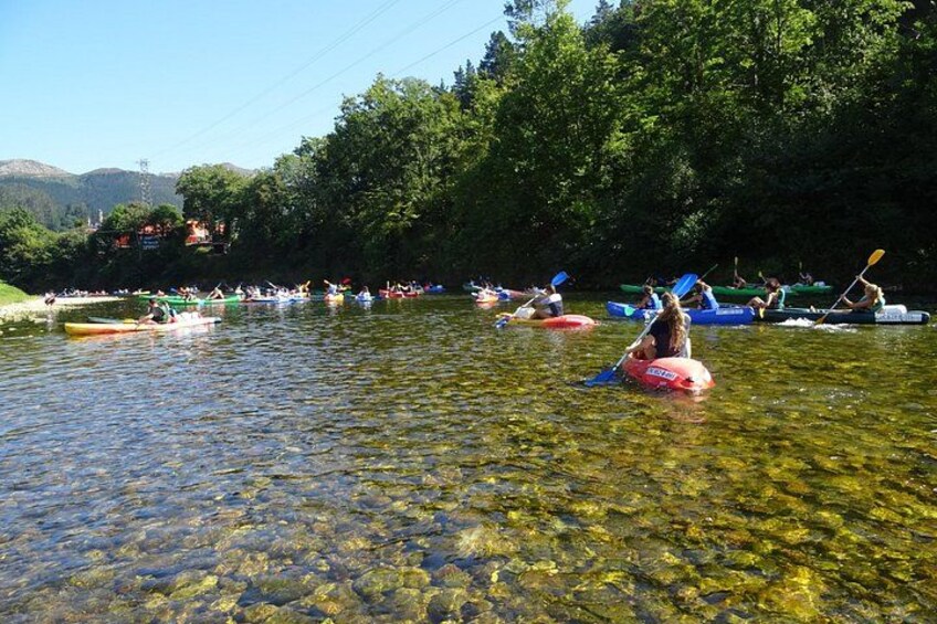 Människor som paddlar kajak på en flod omgiven av träd och kullar. 3