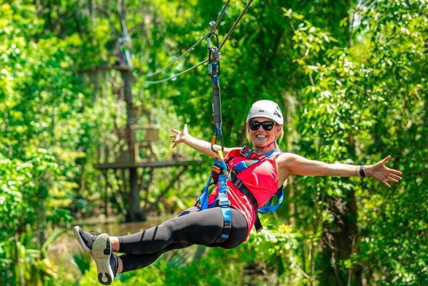En person åker på en zipline genom ett skogsområde. 1