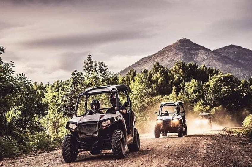 Two off-road vehicles on a dirt road with mountains in the background. 3