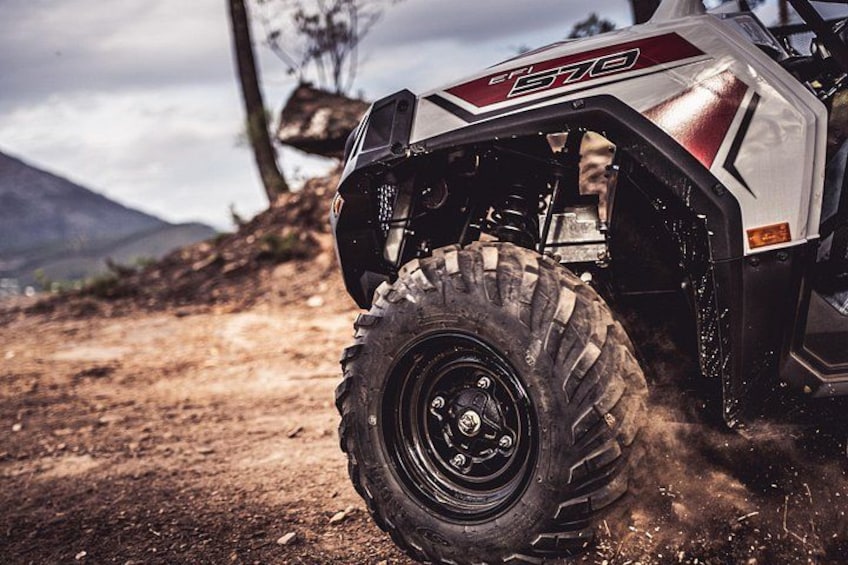 A rugged off-road vehicle on a dirt path with mountains in the background. 2